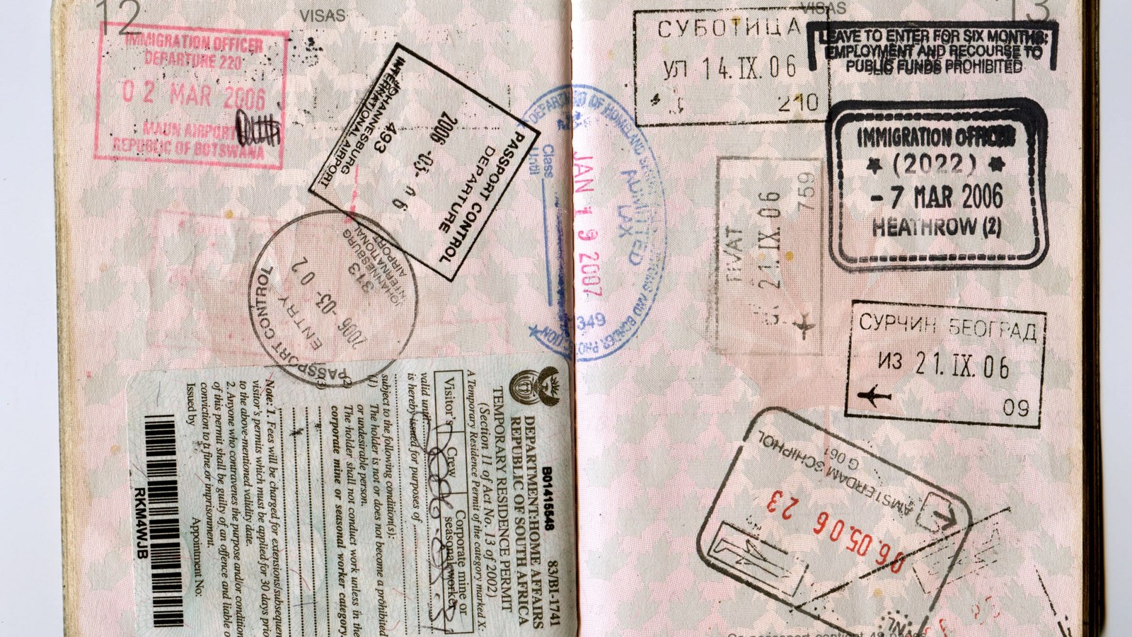 A passport opened to a double page densely covered in immigration and border-control stamps from several countries, printed on security paper with a pale patterned background